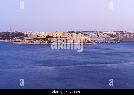 Vue panoramique de nuit depuis les jardins d'Upper Barrakka à Valetta, Malte sur fort St Antonio et Vittoriosa (Birgu) Banque D'Images