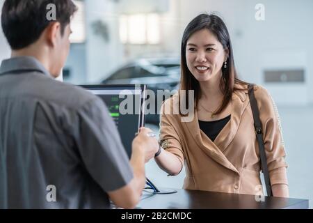 Le mécanicien asiatique a reçu la clé automatique de voiture pour vérifier au centre de maintenance de la salle d'exposition Banque D'Images