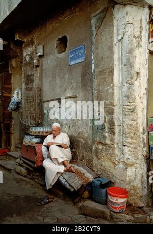 Photographie de voyage - l'homme égyptien lisant dans les ruelles du Caire islamique en Egypte en Afrique du Nord Moyen-Orient - Livre éducation Banque D'Images