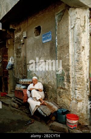 Photographie de voyage - l'homme égyptien lisant dans les ruelles du Caire islamique en Egypte en Afrique du Nord Moyen-Orient - Livre éducation Banque D'Images