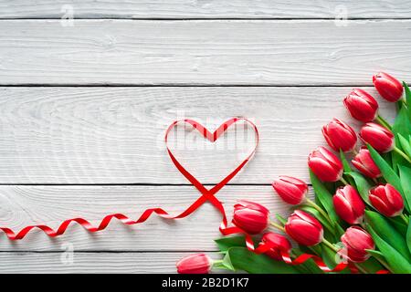 Tulipes rouges et coeur en forme de ruban sur fond en bois. Saint Valentin, Fête Des Mères, Joyeux Anniversaire, Mariage, Fête Des Femmes - Concept Banque D'Images