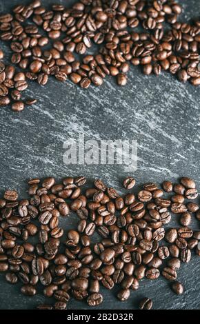 Grains de café dispersés sur une surface noire Banque D'Images