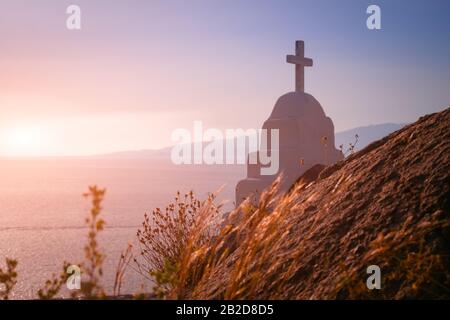 Superbes couleurs de coucher de soleil sur la mer Égée. Croix de l'église orthodoxe, symbole de la religion chrétienne. Île de Mykonos. Grèce Banque D'Images