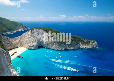 Vue pittoresque sur Navagio Beach ou Shipwreck Beach. Vieux navire après un accident sur le sable dans le lagon entouré de hautes roches. Bateaux flottant turquoise Io Banque D'Images