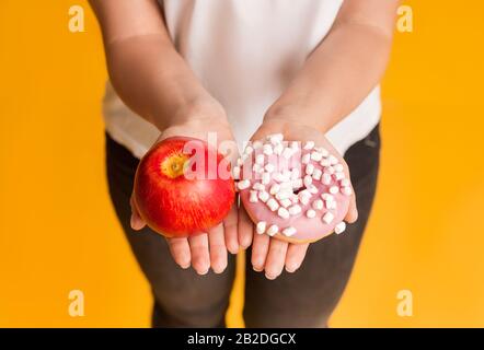 Nutrition Saine. Femme Faisant Le Choix Entre Apple Et Donut Entre Les Mains Banque D'Images