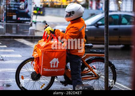 Jeune homme sur un vélo électrique avec le logo takeaway.com fournissant de la nourriture pendant une journée de pluie à Bucarest, Roumanie, 2020 Banque D'Images