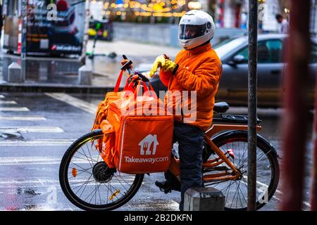 Jeune homme sur un vélo électrique avec le logo takeaway.com fournissant de la nourriture pendant une journée de pluie à Bucarest, Roumanie, 2020 Banque D'Images