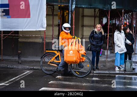 Jeune homme sur un vélo électrique avec le logo takeaway.com fournissant de la nourriture pendant une journée de pluie à Bucarest, Roumanie, 2020 Banque D'Images