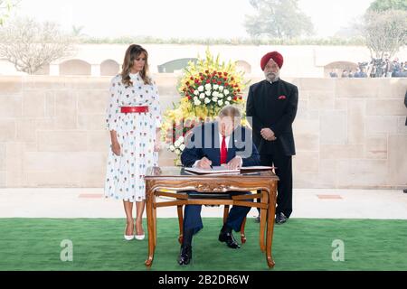 Le président américain Donald Trump et la première dame Melania Trump signent le livre d'or au mémorial de Mahatma Gandhi à Raj Ghat le 25 février 2020 à New Delhi, en Inde. Le ministre d'État indien de l'aviation civile, du logement et des affaires urbaines Hardeep Singh Puri est à droite. Banque D'Images