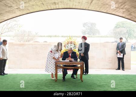 Le président américain Donald Trump et la première dame Melania Trump signent le livre d'or au mémorial de Mahatma Gandhi à Raj Ghat le 25 février 2020 à New Delhi, en Inde. Le ministre d'État indien de l'aviation civile, du logement et des affaires urbaines Hardeep Singh Puri est à droite. Banque D'Images