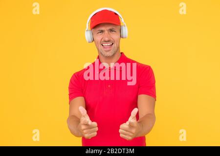 Laissez la musique parler. Heureux homme donner des pouces fond jaune. Profitez de votre musique préférée. Beau gars porter des écouteurs jouant de la musique. Écouter de la musique et chanter sur la chanson. Banque D'Images
