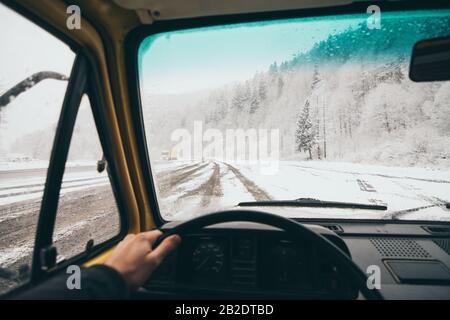 Vue depuis le siège conducteur sur la route enneigée de la terre avec forêt d'hiver sur fond. Banque D'Images