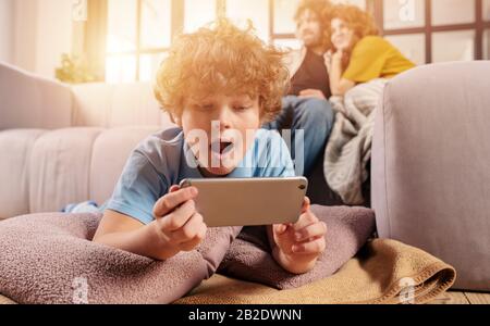 Son joue en ligne avec un smartphone. Concept de dépendance, dépendance, problème Banque D'Images