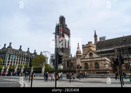 Les touristes marchent près du palais de Westminster tandis que Big Ben est couvert d'échafaudages pendant la restauration. Le London Eye peut être vu en arrière-plan. Banque D'Images