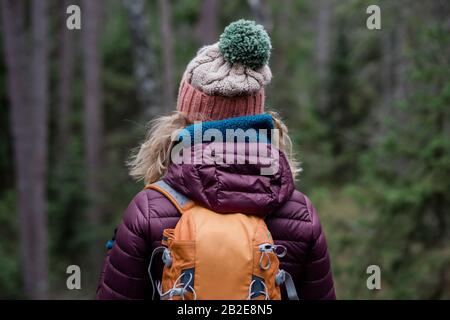 dos d'une femme debout dans une forêt en hiver randonnée avec un sac à dos Banque D'Images