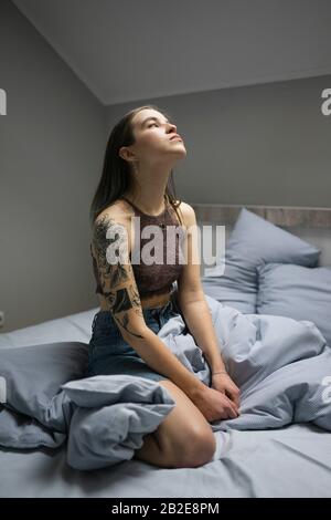 Femme avec tatouage assis sur le lit. Banque D'Images