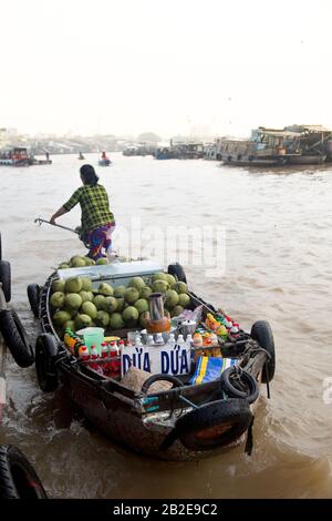 Femme sur bateau vendant des noix de coco et d'autres boissons sur le marché flottant Banque D'Images