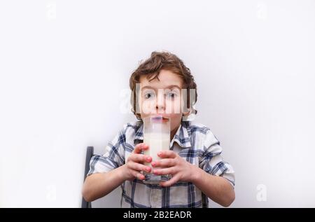 joyeux garçon avec un verre de lait sur fond blanc. Source de calcium. Concept de carence en lactose Banque D'Images