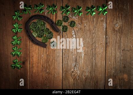 Arrière-plan avec des feuilles et des pièces rouillées en fer à cheval et en trèfle sur le bois rustique. Symbole de Saint-Patrick pour les jours fériés. Charmes chanceux. Vue de dessus, espace de copie. Banque D'Images