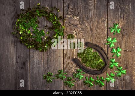 Arrière-plan avec des feuilles et des pièces rouillées en fer à cheval et en trèfle sur le bois rustique. Symbole de Saint-Patrick pour les jours fériés. Charmes chanceux. Vue de dessus, espace de copie. Banque D'Images