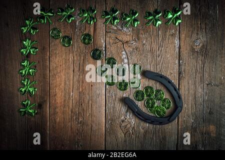 Arrière-plan avec des feuilles et des pièces rouillées en fer à cheval et en trèfle sur le bois rustique. Symbole de Saint-Patrick pour les jours fériés. Charmes chanceux. Vue de dessus, espace de copie. Banque D'Images