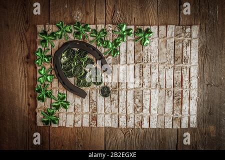 Arrière-plan avec des feuilles et des pièces rouillées en fer à cheval et en trèfle sur le bois rustique. Symbole de Saint-Patrick pour les jours fériés. Charmes chanceux. Vue de dessus, espace de copie. Banque D'Images