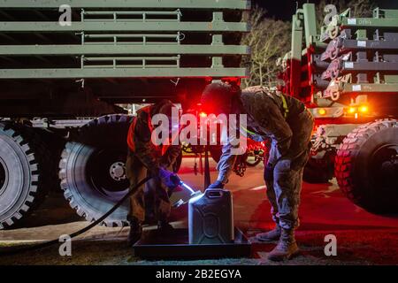 03 mars 2020, Saxe-Anhalt, Burg : un soldat du Bataillon logistique 171 (l) et un soldat de l'armée américaine remplissent un réservoir de réserve de carburant dans la caserne de Clausewitz après avoir ravitaillé un véhicule de l'armée américaine. Le véhicule militaire est transféré d'un dépôt en Belgique à la Pologne pour l'exercice mené par les États-Unis « Europe 2020 » et a été ravitaillé sur le site par des soldats de la Bundeswehr. Dans le cadre de l'exercice à grande échelle, environ 20 000 soldats doivent être transférés des États-Unis à travers l'Allemagne vers l'Europe de l'est. En outre, plusieurs autres exercices sont prévus en Allemagne, en Pologne, en Géorgie et dans le Stat Baltique Banque D'Images