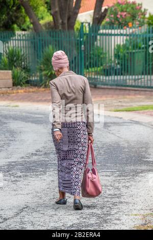 Alberton, Afrique du Sud - une femme africaine noire non identifiée bien habillée marche dans une rue résidentielle de la ville Banque D'Images