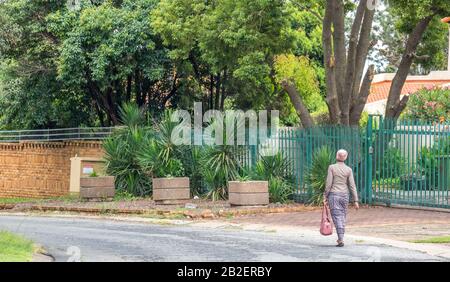 Alberton, Afrique du Sud - une femme africaine noire non identifiée bien habillée marche dans une rue résidentielle de la ville Banque D'Images