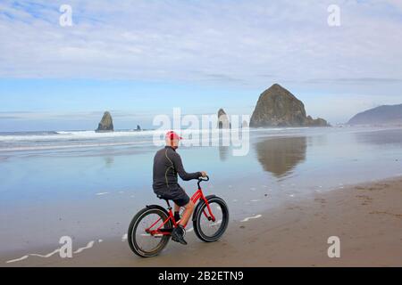 Homme à vélo sur Cannon Beach, Oregon, États-Unis Banque D'Images