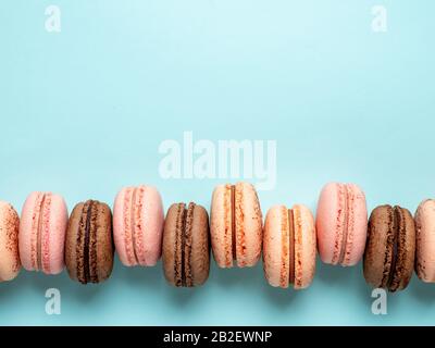 Macarons avec espace de copie. Rangée de macarons ou macarons français parfaits sur fond bleu. Vue de dessus ou plat Banque D'Images