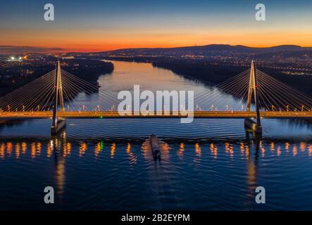 Budapest, Hongrie - vue aérienne sur le magnifique pont de Megyeri illuminé par câble sur le Danube avec ciel bleu et orange après le coucher du soleil Banque D'Images