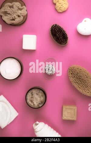 Gommage, lotion, savons, serviette en coton, gant exfoliant pour le soin du corps sur fond rose. Kit spa écologique, plat Banque D'Images