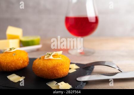 Croquettes maison remplies de fromage avec citron et un verre de vin rouge. Banque D'Images