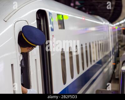 Tokyo, Japon - 13 octobre 2018 : le chef d'un train à grande vitesse Shinkansen de la série N700 contrôle la plate-forme avant le départ de la gare de Tokyo. Banque D'Images