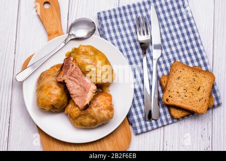 Rouleaux de chou avec viande, riz et légumes dans une plaque blanche sur une table en bois. Feuilles de chou farcies à la viande. Sarma, dolma, Chou farci, golubtsy Banque D'Images