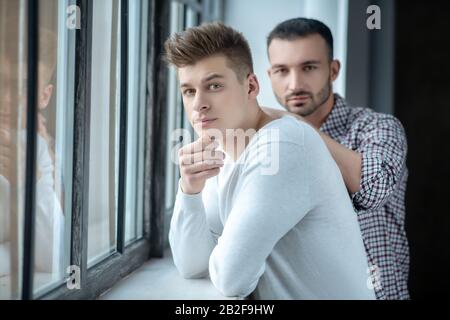 Deux jeunes hommes se tenant près de la fenêtre Banque D'Images