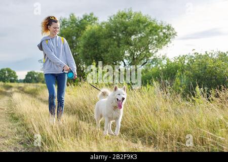 Mode de vie sain actif, jeune fille marchant avec un chien Husky blanc Banque D'Images