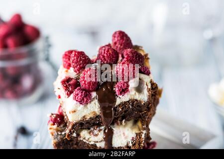 Cheesecake brownies avec framboises empilées sur une plaque. Chocolat fondu. Morceau de gâteau. Dessert Brownie. Cerise et framboise. Saint Valentin. Femmes Banque D'Images