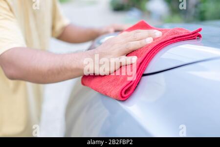 Main de personnes utilisant un tissu rouge pour nettoyer le corps de la voiture de SUV. Concept de voiture de nettoyage ou de lavage Banque D'Images