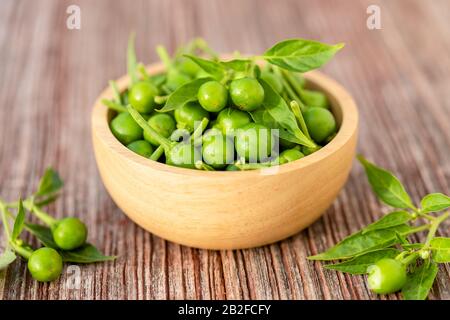 Gros sur le fond de la planche de table, le piment ou les poivrons de cerisier du cercle vert se trouvent dans un bol en bois Banque D'Images