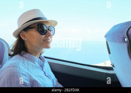 Femme passager dans un chapeau assis en bus regardant la fenêtre Banque D'Images