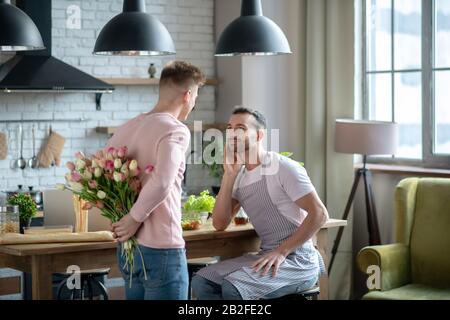 Homme avec un bouquet derrière et l'autre assis en face. Banque D'Images