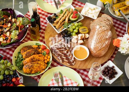 Vue sur le dessus d'un bol de salade, pain, viandes, fruits et autres aliments, prêts à manger sur une table extérieure avec une nappe de Vichy rouge, décorée avec Banque D'Images