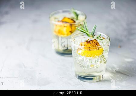 Deux verres de vin et de tonique avec citron rouge, romarin et coriandre est un cocktail rafraîchissant parfaitement équilibré. Sur fond clair, Banque D'Images