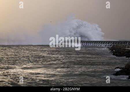 Une grande vague éclabousser sur la jetée au coucher du soleil. Bouche du Douro. Banque D'Images