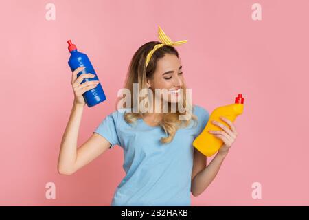 Une femme souriante millénaires choisit une bouteille de fournitures de nettoyage Banque D'Images