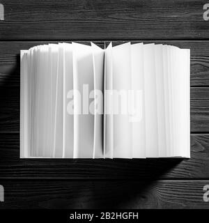 Un livre blanc avec des pages blanches se trouve sur un fond en bois noir Banque D'Images