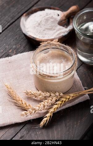 Entrée de levain de pétillant maison, mélange fermenté d'eau et de farine à utiliser comme levain pour la cuisson du pain, sur table en bois Banque D'Images