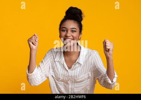 Joyeuse Fille Levant Les Mains Dans L'Excitation, Célébrant Le Succès Avec Des Poings Serrés Banque D'Images